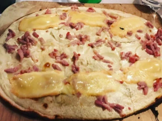 Tarte flambée gratinée servie sur sa planche